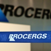 Fita delimitadora de acesso com marca da Procergs em primeiro plano, com parede ao fundo também com marca da Procergs no saguão de entrada do prédio