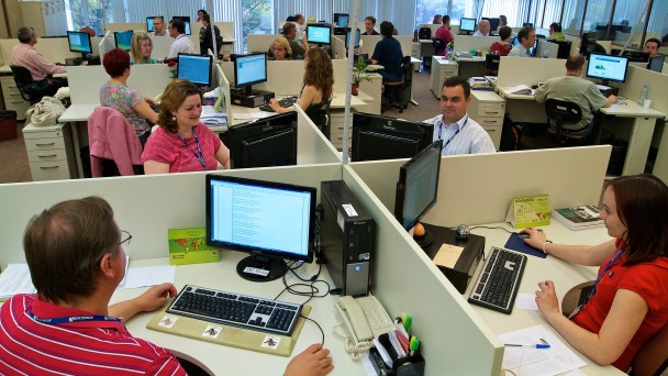 Ambiente com muitos funcionários da Procergs trabalhando em suas mesas com computadores