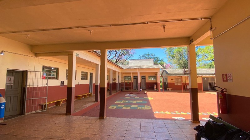 Vista do pátio interno da escola, com um cachorro ao fundo.