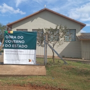 Fachada da escola com placa anunciando obra.