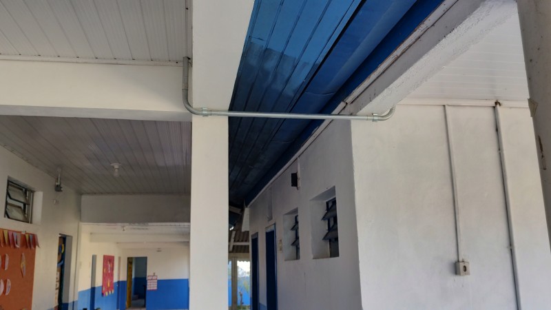 Corredor interior da escola pintada em branco e azul.