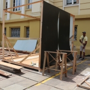 Na calçada, em frente ao antigo prédio pintado em tons de amarelo, estão três homens preparando os tapumes da construção.