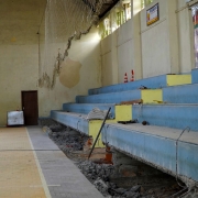 Dentro do ginásio da escola, vê-se a arquibancada com o primeiro degrau demolido.