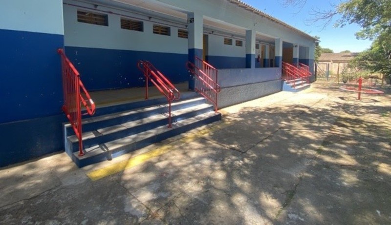Foto da lateral do prédio da escola com escadas com corrimãos.
