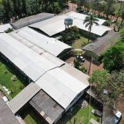 Foto aérea dos prédios da escola. Há uma caixa d'água ao centro, carros estacionados e árvores circundando os prédios.