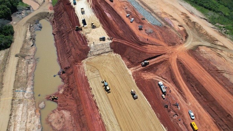 Foto aérea da construção da barragem com patrolas trabalhando.