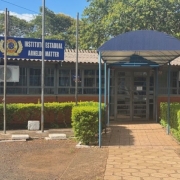 Foto da fachada da escola, com um toldo azul em frente à entrada.