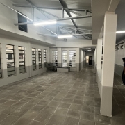 Foto interna de uma escola pintada em tons de bege. Um aluno caminha à direita.
