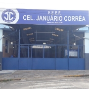 Foto da fachada da escola, térrea, pintada em tons de azul. Na entrada, há um letreiro com o nome da escola.