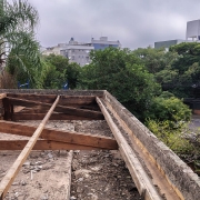  Foto tirada do alto de um telhado, cujas telhas foram retiradas e onde se pode ver o madeirame.