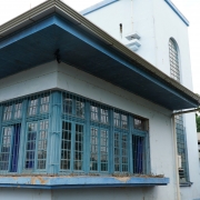 Foto da fachada de uma escola, um prédio de dois pisos pintado em tons de azul.