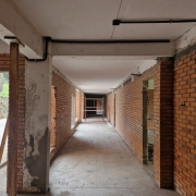    Foto de um corredor de escola, em tijolo à vista, passando por obras.