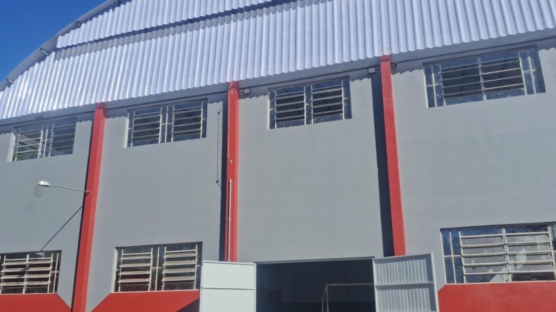 Foto de um ginásio de escola pintado de cinza e vermelho.