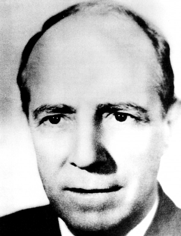 Retrato em preto e branco de um homem branco quase careca vestindo terno.