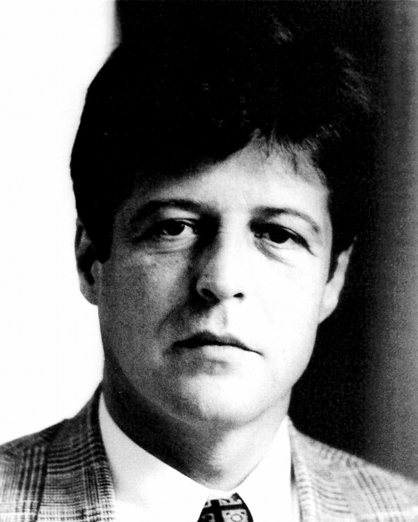 Foto em preto e branco de um homem branco de cabelos escuros e vestindo terno e gravata.