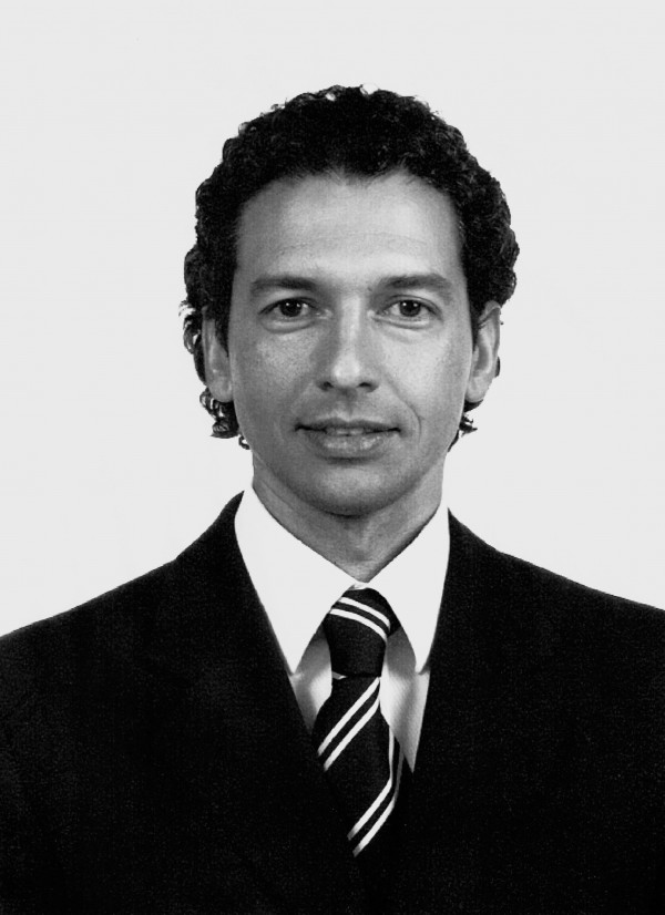 Retrato em preto e branco de um homem branco de cabelos pretos usando terno e gravata.