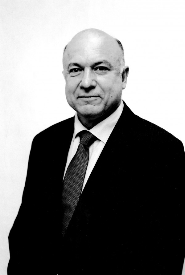 Foto em preto e branco de um homem branco careca usando terno e gravata.