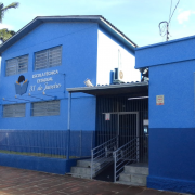 Prédio azul de dois pisos da escola, com letreiro com o nome da instituição.