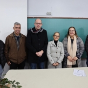 Grupo de pessoas posa para foto entre uma mesa e um quadro negro.