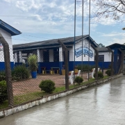 Em primeiro plano, uma calçada com o cimento ainda úmido. Atrás, os prédios térreos da escola, separados por uma cerca.